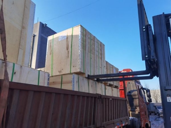 The forklift is loading the wooden cases onto the truck.